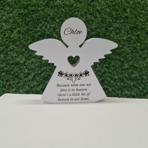 Detailed view of engraved message on wooden memorial angel: 'Because someone we know is in heaven, there's a little bit of heaven in our home.