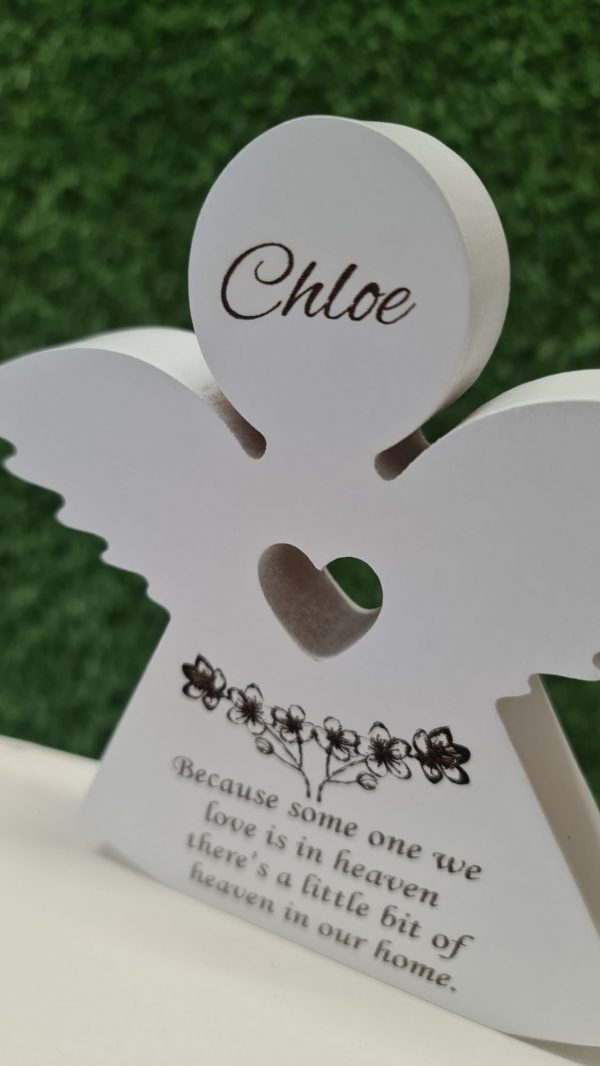 Close-up of engraved flowers and heart on personalised wooden memorial angel